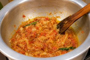 Cooking tomato onion masala in a pot for Easy Ridge Gourd and Split Chickpeas Curry